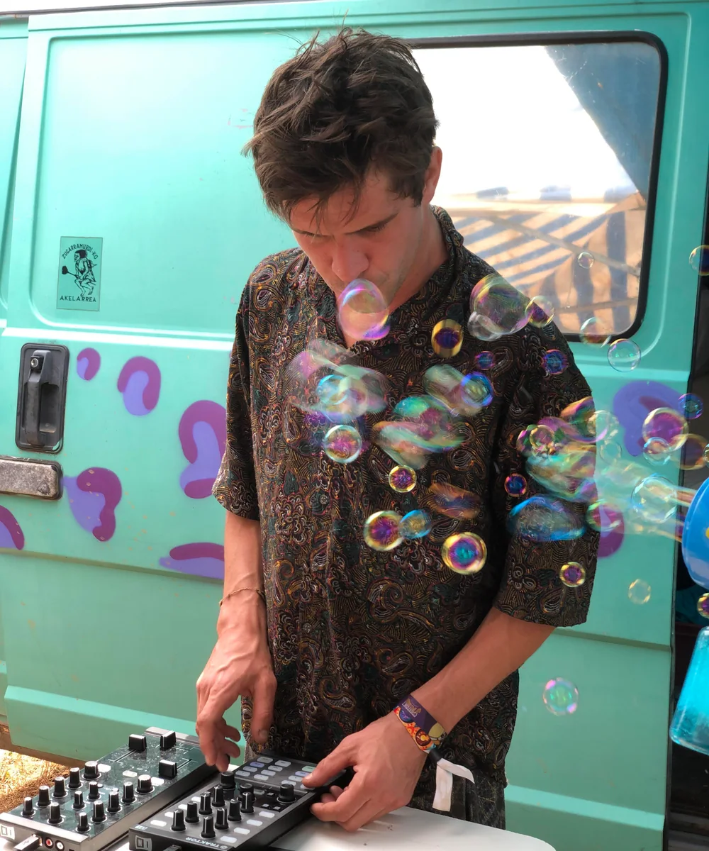 Cham’Art performing an electronic set beside a turquoise van