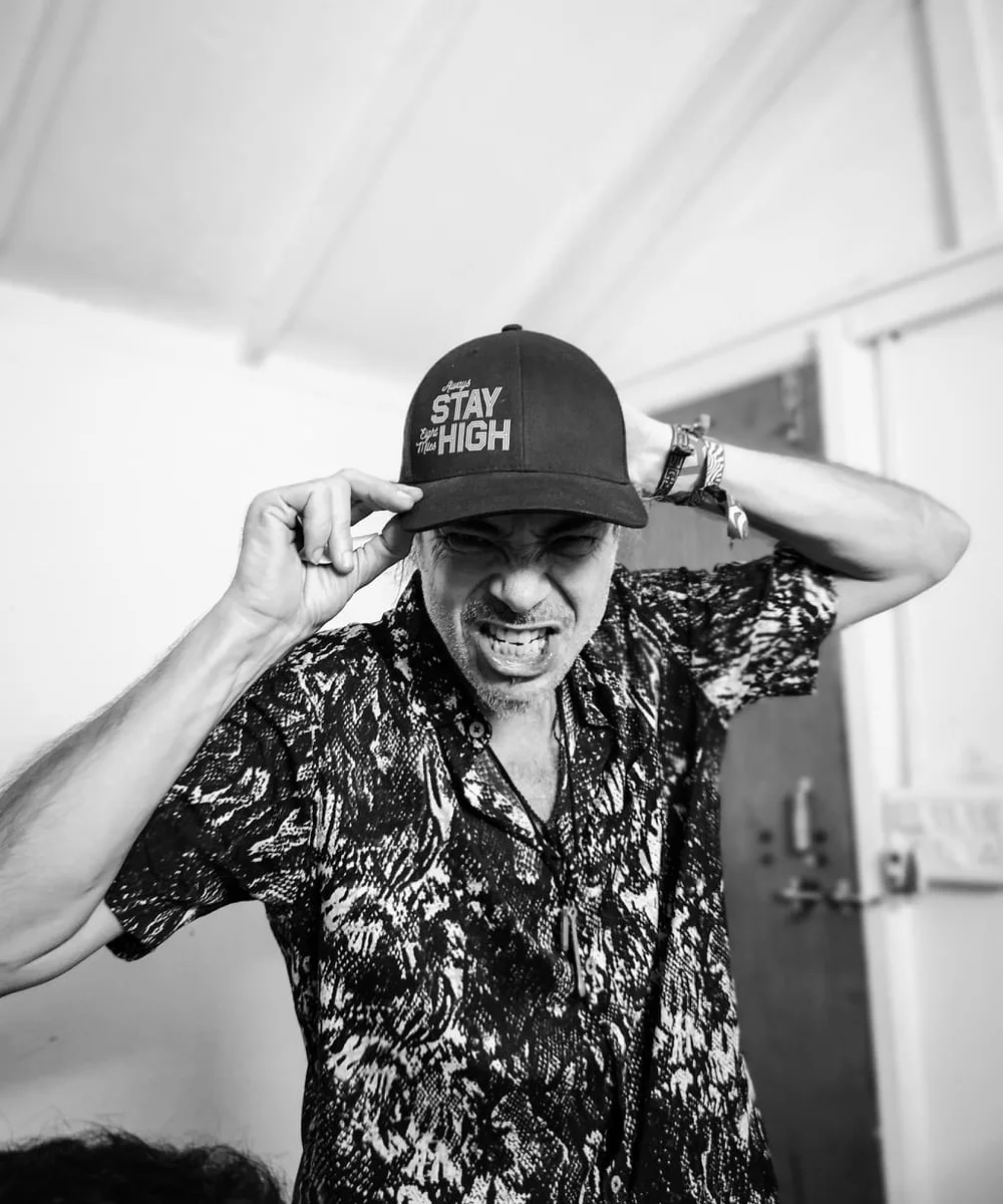 Black-and-white portrait of NeLiO wearing glasses and a cap
