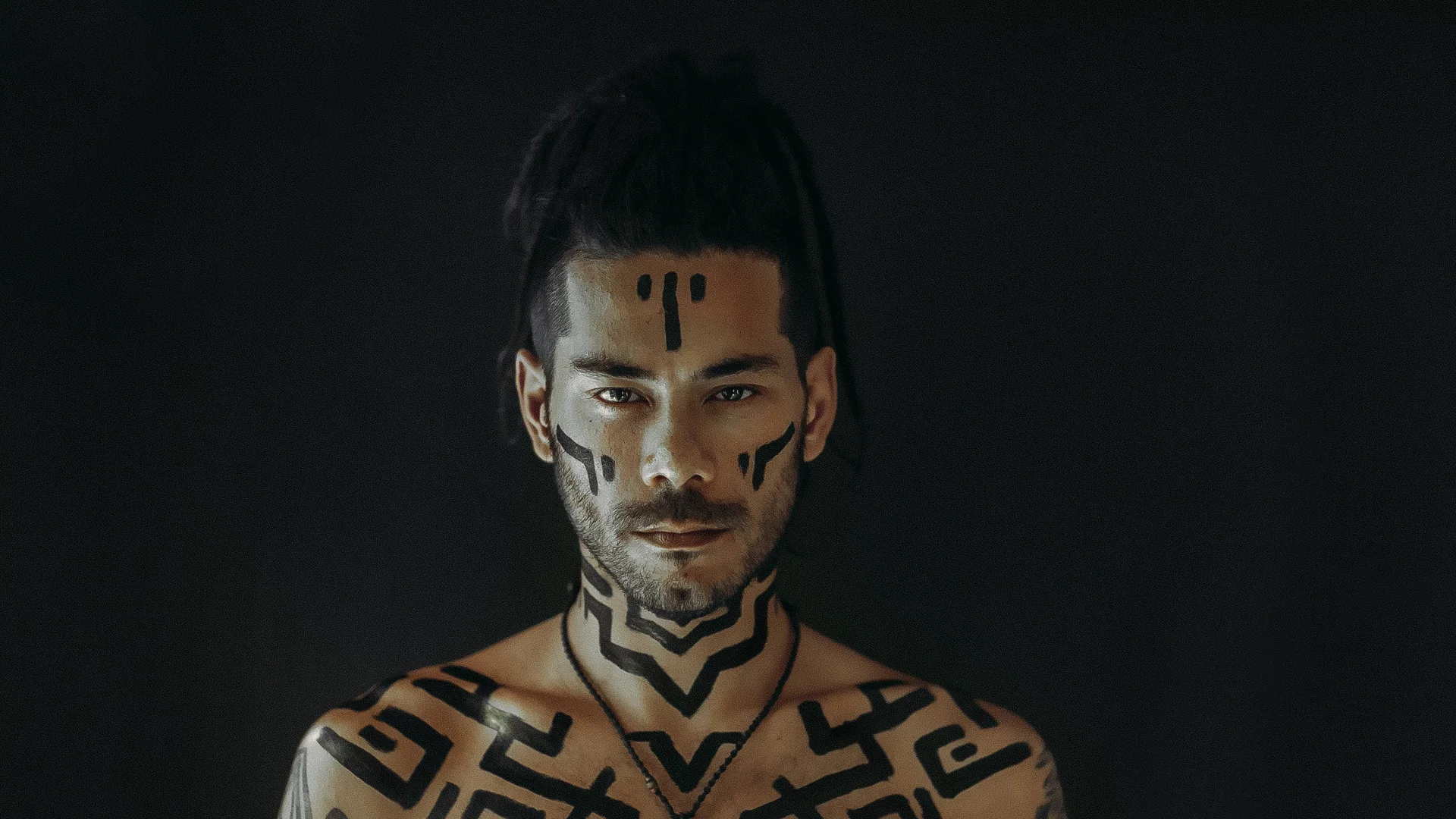 Satrip in a dark studio portrait with geometric body paint